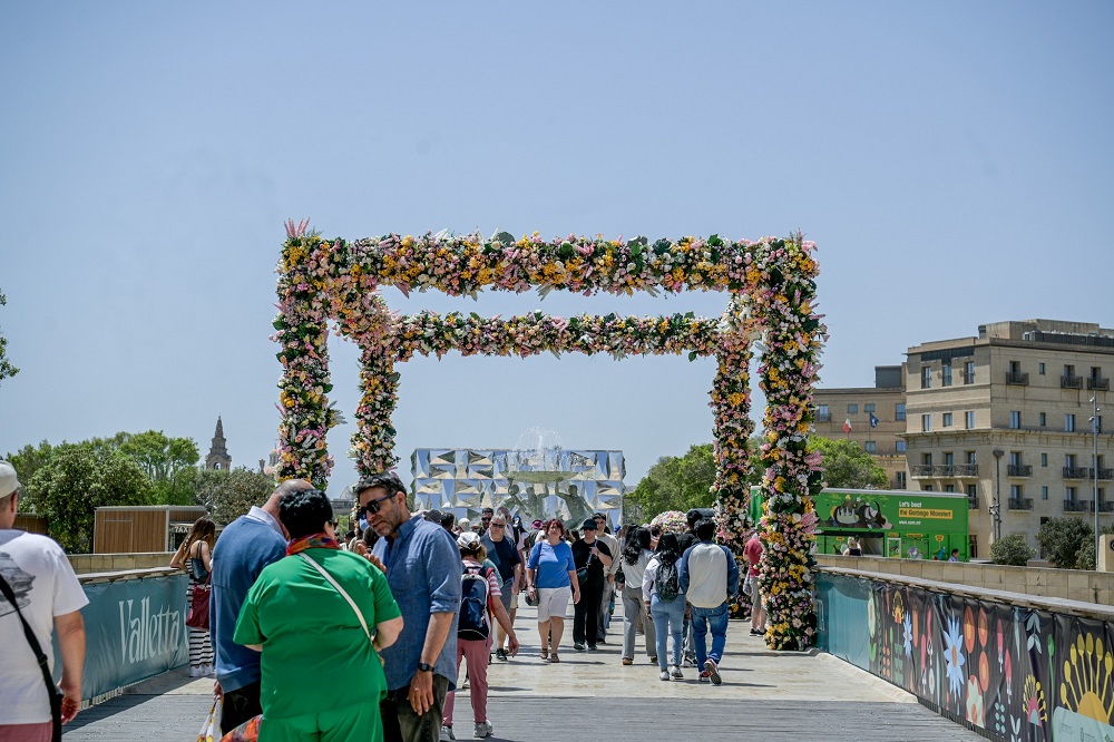 Valletta Green Festival floral arch installation at the entrance to Valletta with families and visitors walking through.